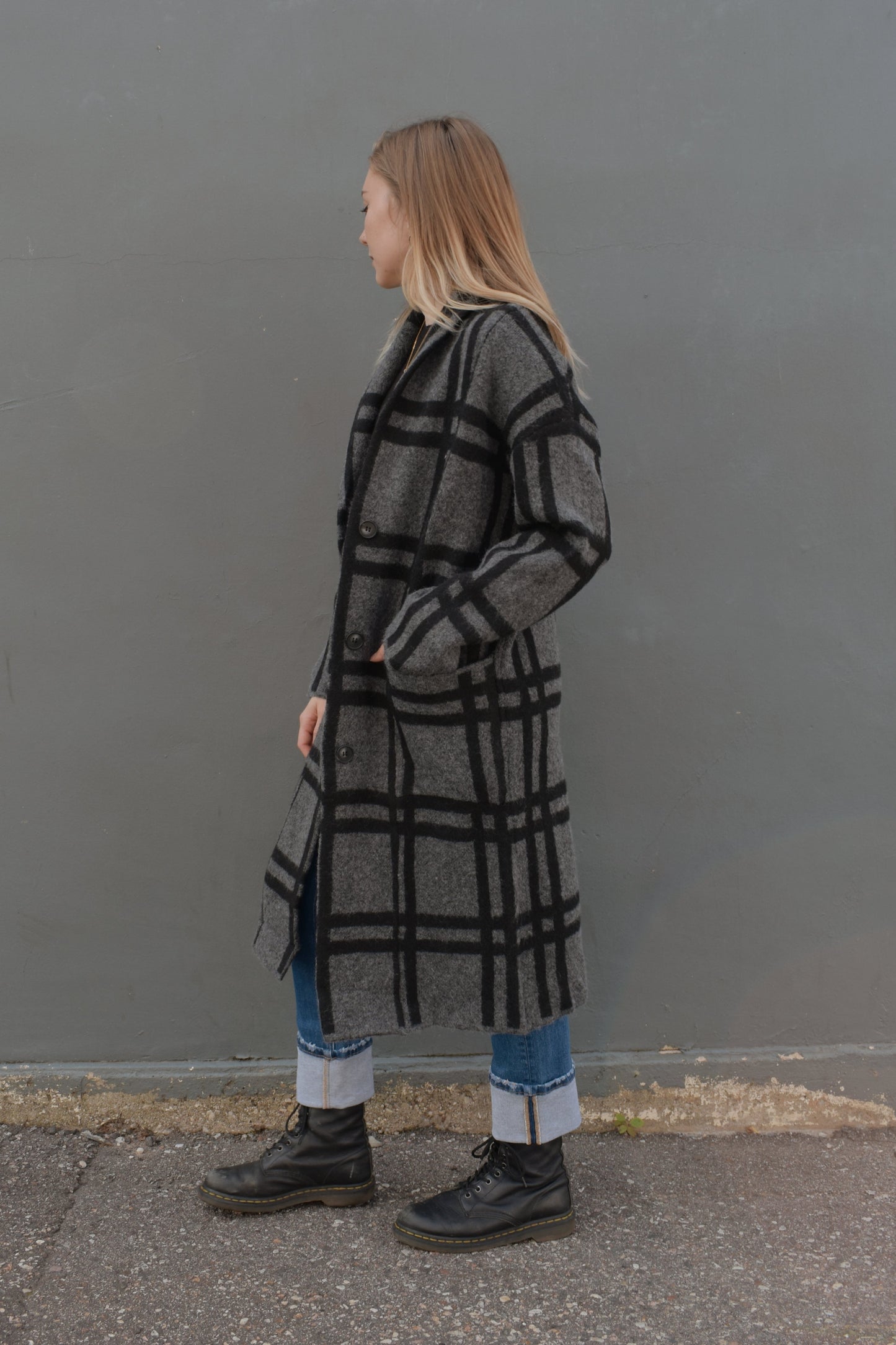 black and grey wide pattered plaid jacket that feels like a cardigan and coat mix, front patch pockets, 3 front buttons for enclosure, folded collar, slightly oversized, drop shoulder, hits at mid calf.